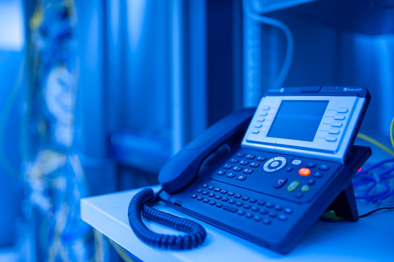 services-02 Close-up of a modern office phone in blue lighting. Ideal for tech and business themes.