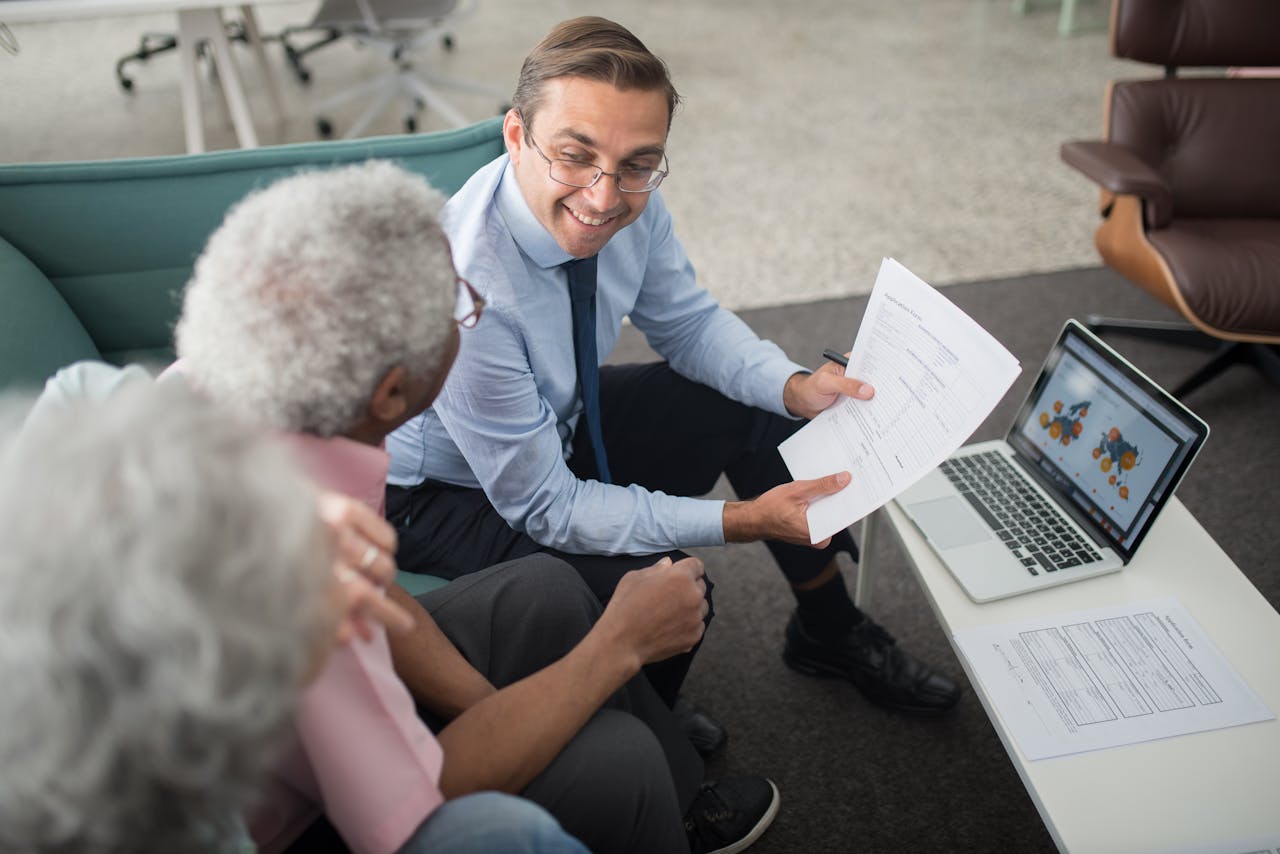 services-04 Financial advisor discussing documents with senior clients in an office setting, showcasing a collaborative consulting session.